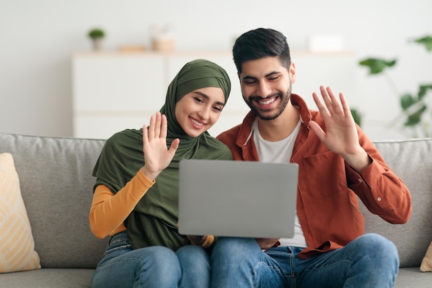 Appel vidéo des conjoints du Moyen-Orient à l'aide d'un ordinateur portable saluant à l'intérieur