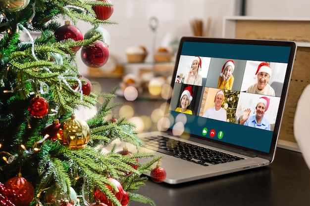 Appel vidéo avec des enfants divers et heureux sur un ordinateur portable dans son atelier. Concept d'auto-isolement et de célébration virtuelle en ligne à la maison. Noël