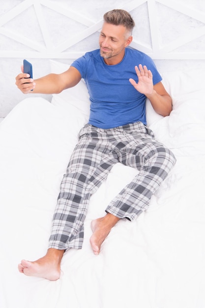 Appel vidéo homme avec téléphone porter pyjama bonjour appel vidéo homme avec téléphone au lit