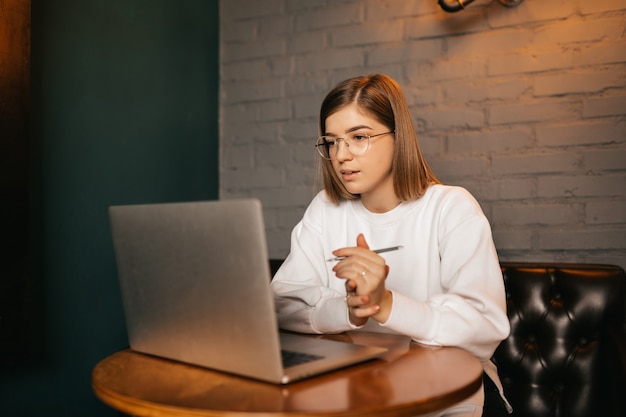 Appel vidéo, jeune femme blanche communique via vidéo en ligne à une grande distance, en regardant l'écran d'un ordinateur portable numérique, conversation fascinante.