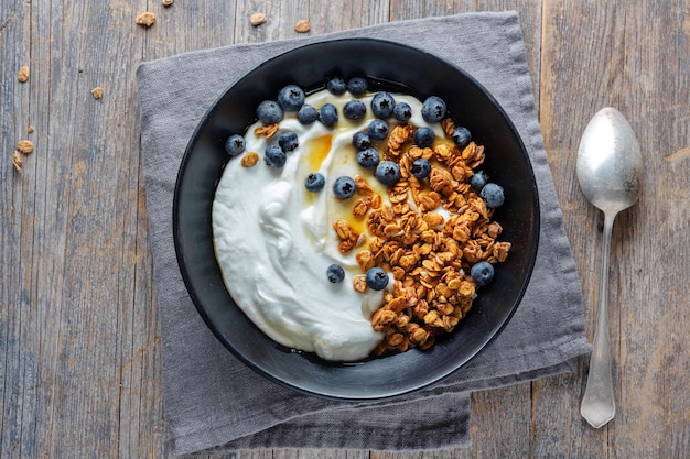 Appétissant muesli maison avec baies et yaourt servi dans un bol sur fond de bois.