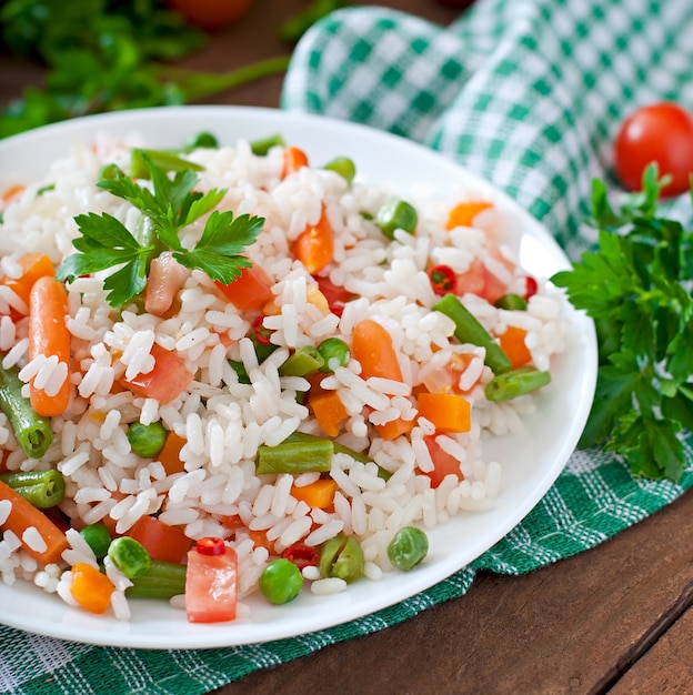 Appétissant riz sain avec des légumes en plaque blanche sur une table en bois