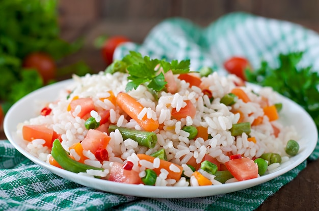 Photo appétissant riz sain avec des légumes en plaque blanche sur une table en bois