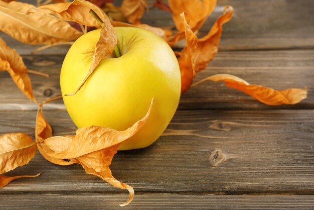 Apple avec des feuilles séchées sur fond de bois