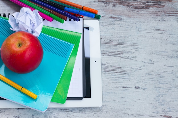 Apple avec des fournitures scolaires sur table en bois blanc