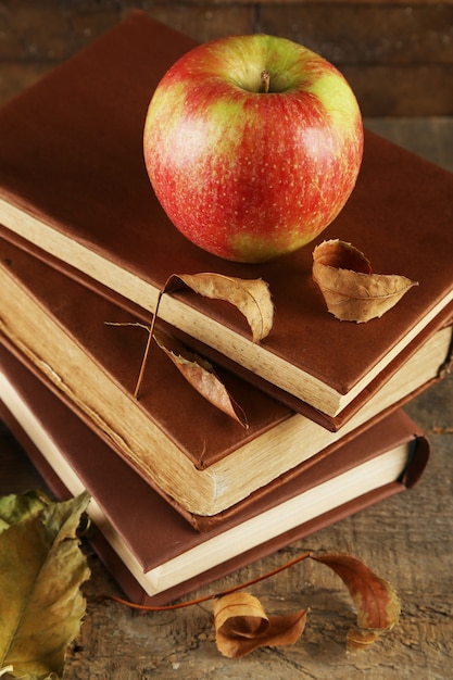 Photo apple avec des livres et des feuilles sèches sur bois