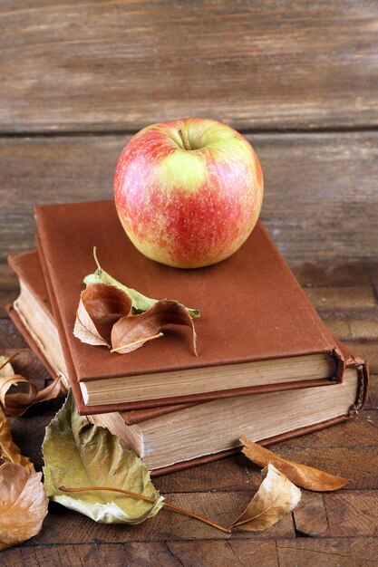 Apple avec des livres et des feuilles sèches sur fond de bois