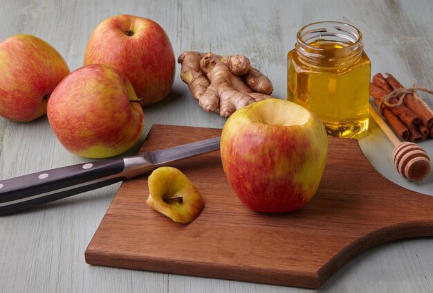 Apple préparé pour la cuisson au four entouré d'ingrédients avec du miel, de la cannelle et du gingembre, se trouve sur une table en bois bleue