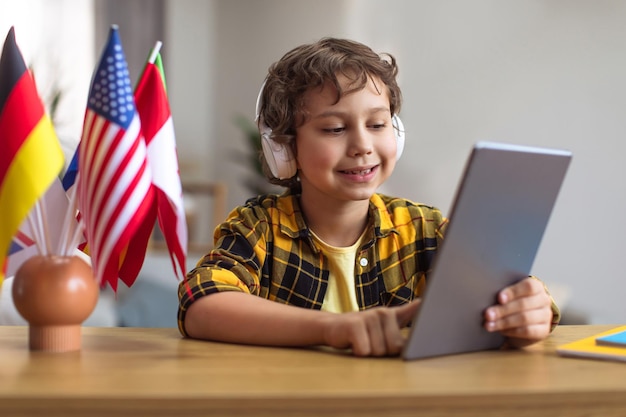 Application d'apprentissage en ligne Mignon petit garçon élève utilisant une application éducative sur une tablette numérique et écoutant l'enseignant