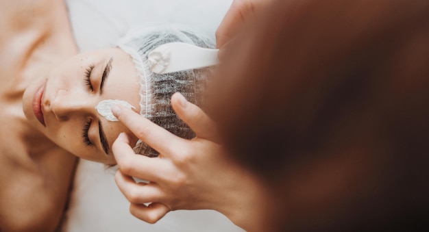 Application d'un masque de cosmétologie sur le visage d'une femme au spa salon soins du visage beauté soins de la peau