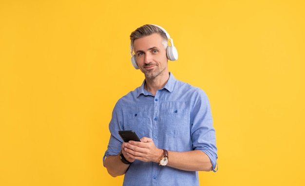 Application de musique mobile nouvelle application gars dans les écouteurs discuter sur smartphone homme écouter de la musique et tenir le téléphone vie moderne et style de vie gars bavarder dans les écouteurs playlist musicale