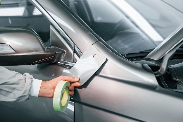 Application d'une nouvelle couleur Réparateur automobile caucasien en uniforme travaille dans le garage