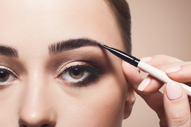 Application d'ombre à sourcils, maquillage de modélisation des sourcils, gros plan des yeux. Visage de modèle féminin avec maquillage de mode, concept de beauté