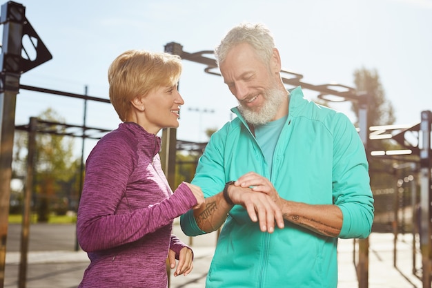 Photo application de remise en forme couple familial d'âge mûr heureux en vêtements de sport vérifiant les résultats de l'entraînement tout en