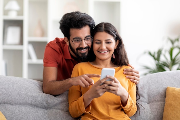 Application de shopping heureux couple indien utilisant un smartphone à la maison ensemble