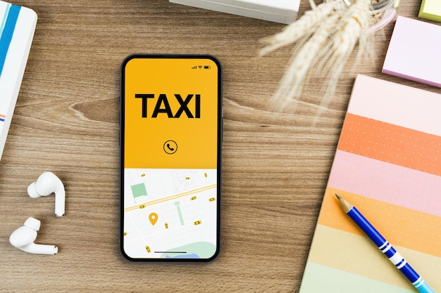 Application Taxi Service sur l'écran du smartphone sur la table en bois. Environnement de bureau. Fournisseur de services de mobilité dans le monde entier.