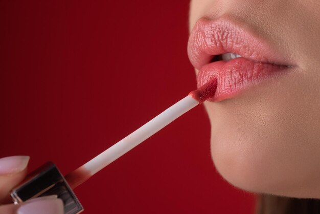 Appliquer du rouge à lèvres om bouffantes lèvres sexy Peindre les lèvres avec du rouge à l'oreille brillant de près Concept de correction des lèvres pampering Le rouge à linge brillant sur la lèvre pleine bouffante sensuelle