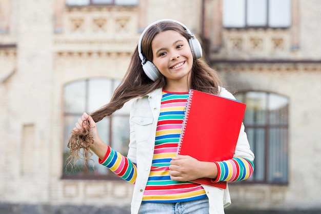 Appliquer une pédagogie innovante à l'enseignement à l'école en ligne. Enfant heureux écoutant un livre en ligne jouant dans des écouteurs. Petite fille aime apprendre en ligne. Un nouveau cours d'anglais est disponible en ligne.