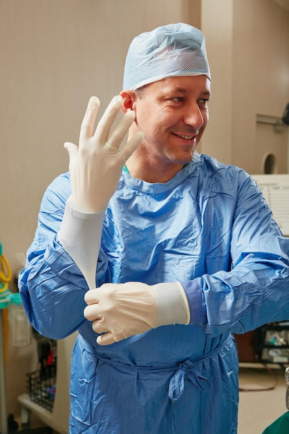 Photo apporter des années d'expérience et de positivité aux urgences photo d'un chirurgien mettant des gants chirurgicaux en préparation d'une intervention chirurgicale