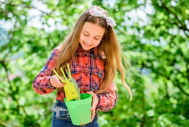 Appréciant son travail avec les plantes printemps village pays petite fille enfant dans la forêt petite fille avec des outils de jardinage jour de la terre écologie environnement Bonne fête des enfants ferme d'été Enfance heureuse