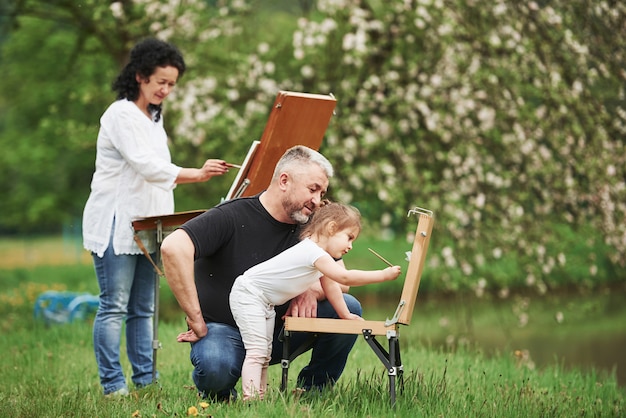 Apprendre cet art. Grand-mère et grand-père s'amusent à l'extérieur avec leur petite-fille. Conception de peinture