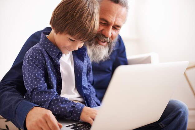 Apprendre avec grand-père Photo d'un grand-père et d'un petit-fils utilisant un ordinateur portable ensemble