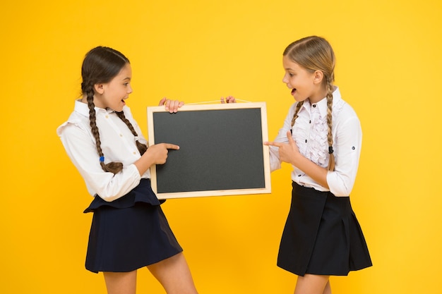 Apprendre en s'amusant à la leçon Mignons petits écoliers récitant une leçon au tableau noir sur fond jaune Petites écolières ayant une leçon à l'école primaire La leçon la plus intéressante de tous les temps