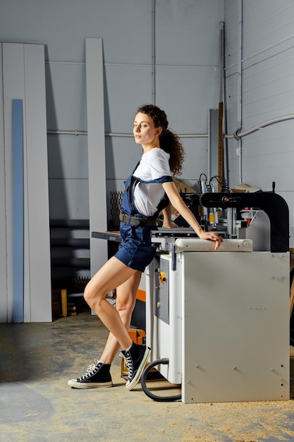 Apprentie femme appuyée contre une machine à bois