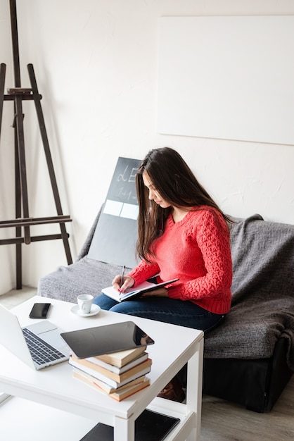 Apprentissage à distance. E-learning. Jeune femme latine enseignant l'anglais en ligne à l'aide d'un ordinateur portable assis sur le canapé