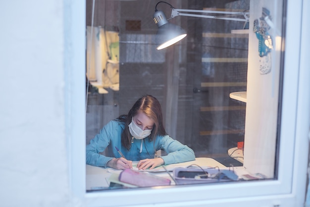 L'apprentissage à distance en quarantaine, une adolescente dans un masque médical faisant des leçons