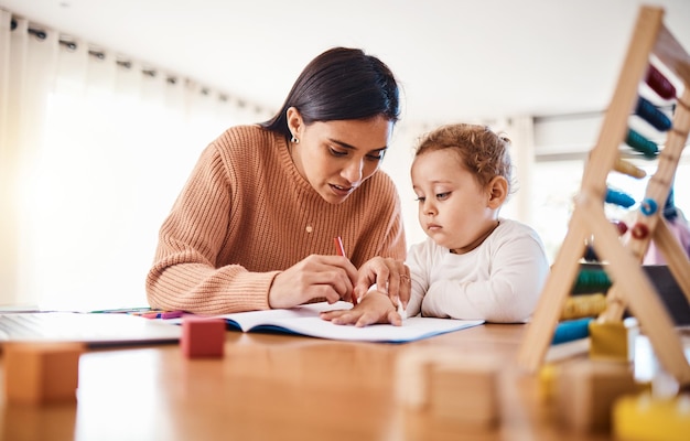 Apprentissage de l'éducation et mère avec enfant dessinant dans un livre à la maison pour étudier les devoirs ou l'école à la maison Croissance du développement précoce et garçon créatif avec maman lui enseignant l'art de la liaison et des soins