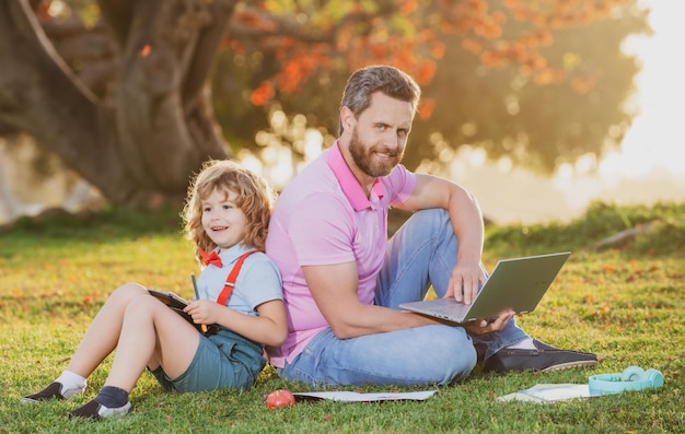 Apprentissage en plein air Père avec son fils dans le parc préparant ses devoirs