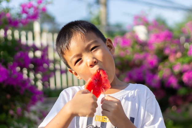 Photo appy garçon enfant asiatique mangeant et tenant une pastèque dans ses mains