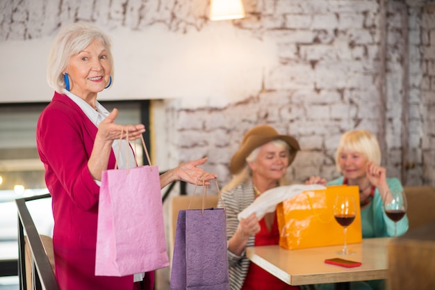 Après les achats. Femmes âgées gaies avec des sacs à provisions semblant heureuses