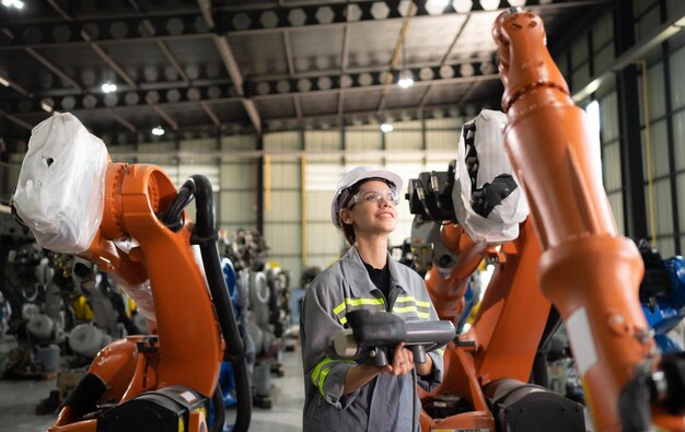 Après avoir installé un programme sur le bras robotique, une ingénieure avec un contrôleur de bras robotique effectue un test