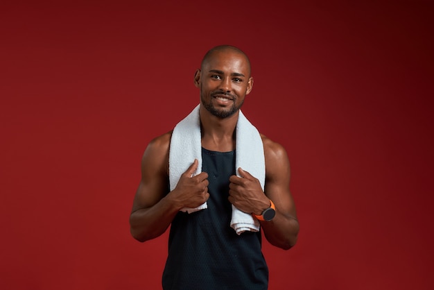 Après l'entraînement, un homme afro-américain joyeux avec une serviette sur les épaules regardant la caméra avec