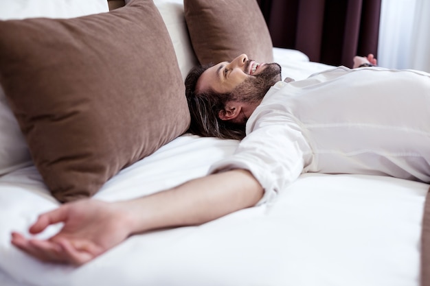 Après le travail. Joyeux homme ravi souriant tout en profitant de sa relaxation