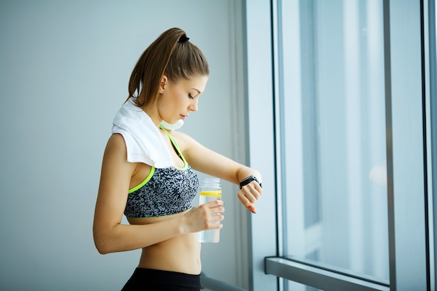 Aptitude. Belle fille sportive en regardant les montres