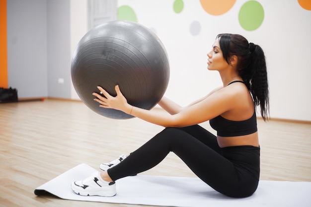 Aptitude. Jeune femme à l'entraînement avec ballon de fitness