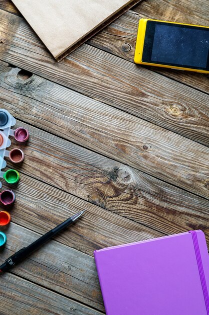 Aquarelles, crayons de couleur et carnet de croquis sur table en bois. Photo à plat avec un espace vide pour le logo, le texte.