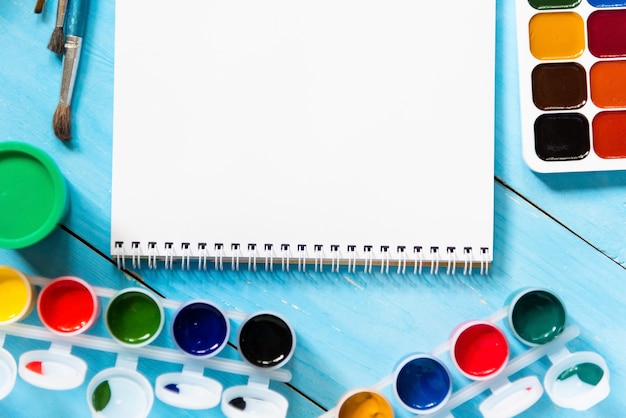 Aquarelles et gouache pour la créativité des enfants sur une table bleue. Copiez l'espace.