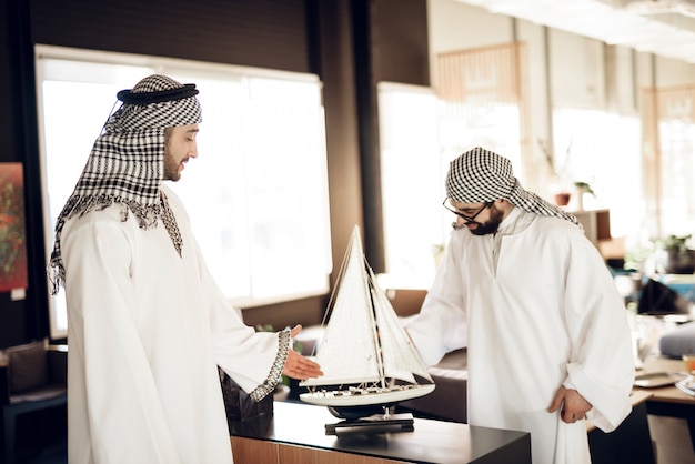 Arab montre un modèle de bateau à un ami au bureau.