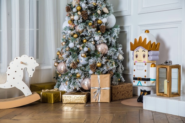 Arbre du Nouvel An décoré de boîtes et cadeaux, cheval à bascule et casse-noisette