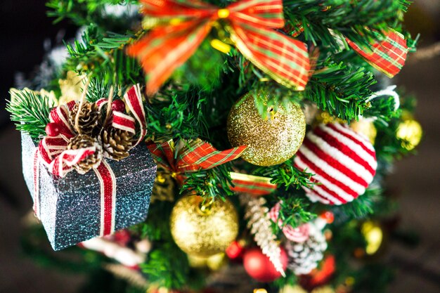 Arbre de Noël assemblé avec des ornements. Boules rouges, argentées et dorées, coffrets cadeaux, lumières, Père Noël et autres. Mise au point sélective.