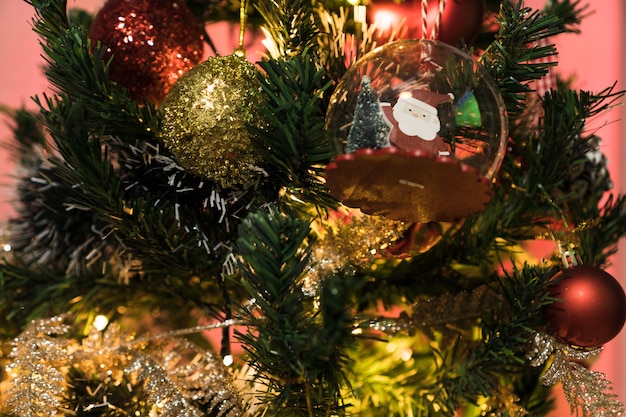 Arbre de Noël assemblé avec des ornements. Boules rouges, argentées et dorées, coffrets cadeaux, lumières, Père Noël et autres. Mise au point sélective.