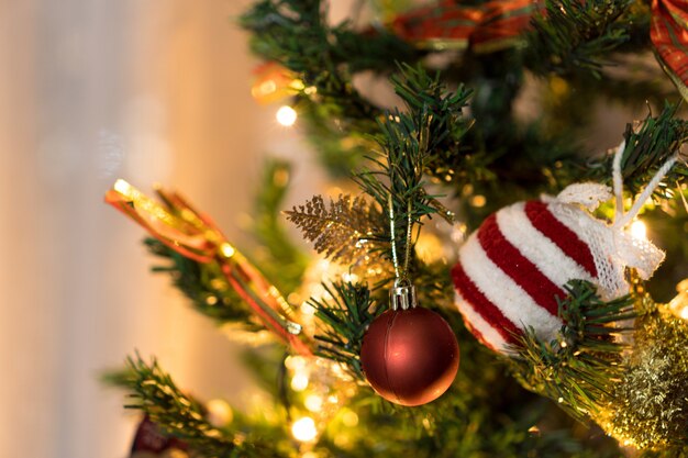 Arbre de Noël assemblé avec des ornements. Boules rouges, argentées et dorées, coffrets cadeaux, lumières, Père Noël et autres. Mise au point sélective.