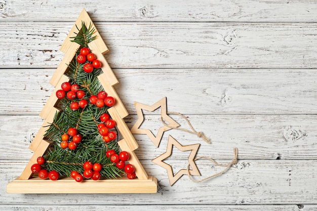 Arbre de noël en bois avec des branches de sapin à l'intérieur décoré de baies de sorbier avec espace de copie