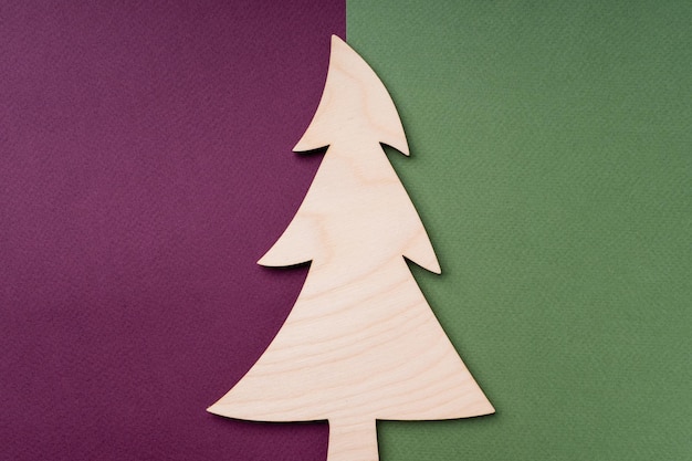 Un arbre de Noël en bois sur un fond de papier rouge et vert Arrière-plan naturel de la nouvelle année pour une carte postale Composition avec décor de Noël espace de copie à plat vue supérieure