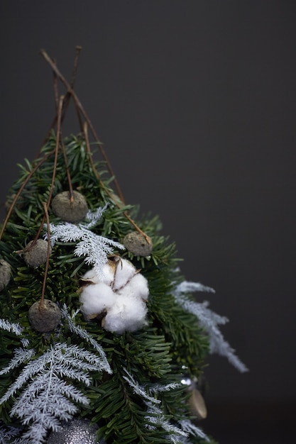 Arbre de Noël en branches de sapin et décoré de matériaux naturels et de boules sur dark