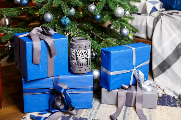 Arbre de Noël avec des cadeaux bleus et argentés dans une salle de Noël blanche. Maison joliment décorée avec un arbre argenté et bleu et des cadeaux pour Noël.